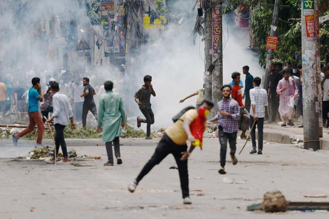 Des manifestants courent dans plusieurs sens au milieu de nuages de gaz lacrymogène, un manifestant au premier plan (habillé d'un foulard rouge cachant le bas de son visage) lance un projectile